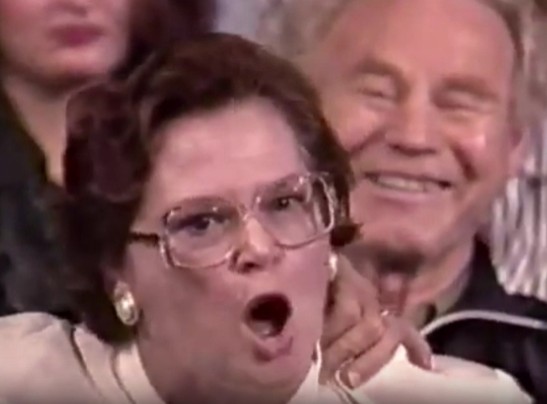Screenshot from Carl Crew’s appearance on Maury Povich, showing a woman in the foreground feigning outrage while a man behind her laughs openly at the spectacle.