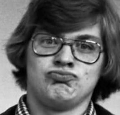 Black-and-white high school–era photo of Jeff Dahmer wearing glasses, tilting his head slightly, and puckering his lips in an exaggerated, playful expression, contrasting with later depictions of him as emotionless.