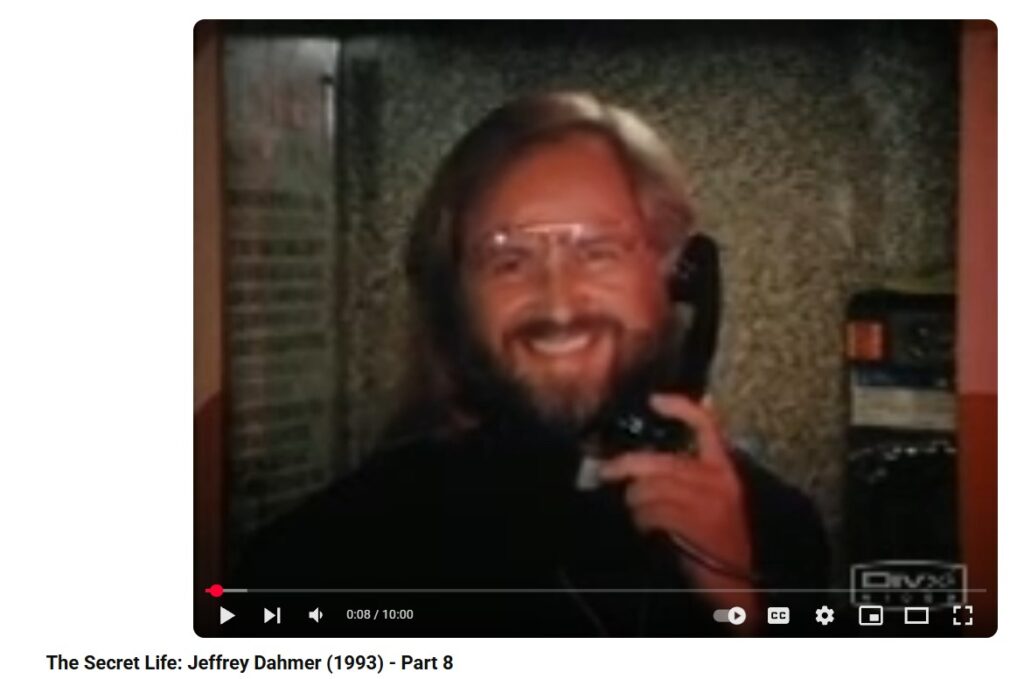 Still from Carl Crew's film The Secret Life: Jeffrey Dahmer showing a grinning Roman Catholic priest calling Jeff Dahmer at a bar.